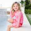 girl sitting on the side of a swimming pool wearing the long sleeve rash top and matching splash jammer duo
