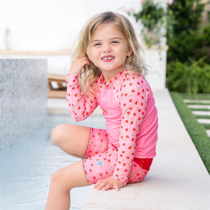 girl sitting on the side of a swimming pool wearing the long sleeve rash top and matching splash jammer duo