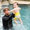 baby in the pool with dad swimming wearing the happy nappy swim diaper lemon print yellow and blue
