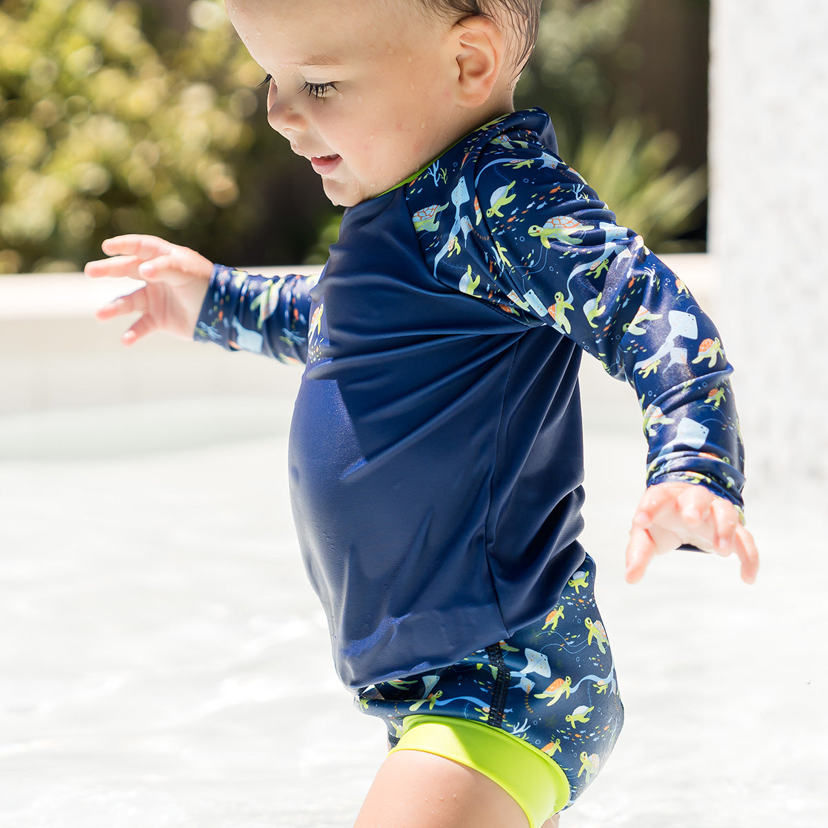 little boy wearing long sleeve rash top turtle tide and matching happy nappy 