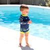 little boy stood next to a swimming pool wearing the long sleeve rash top with matching happy nappy