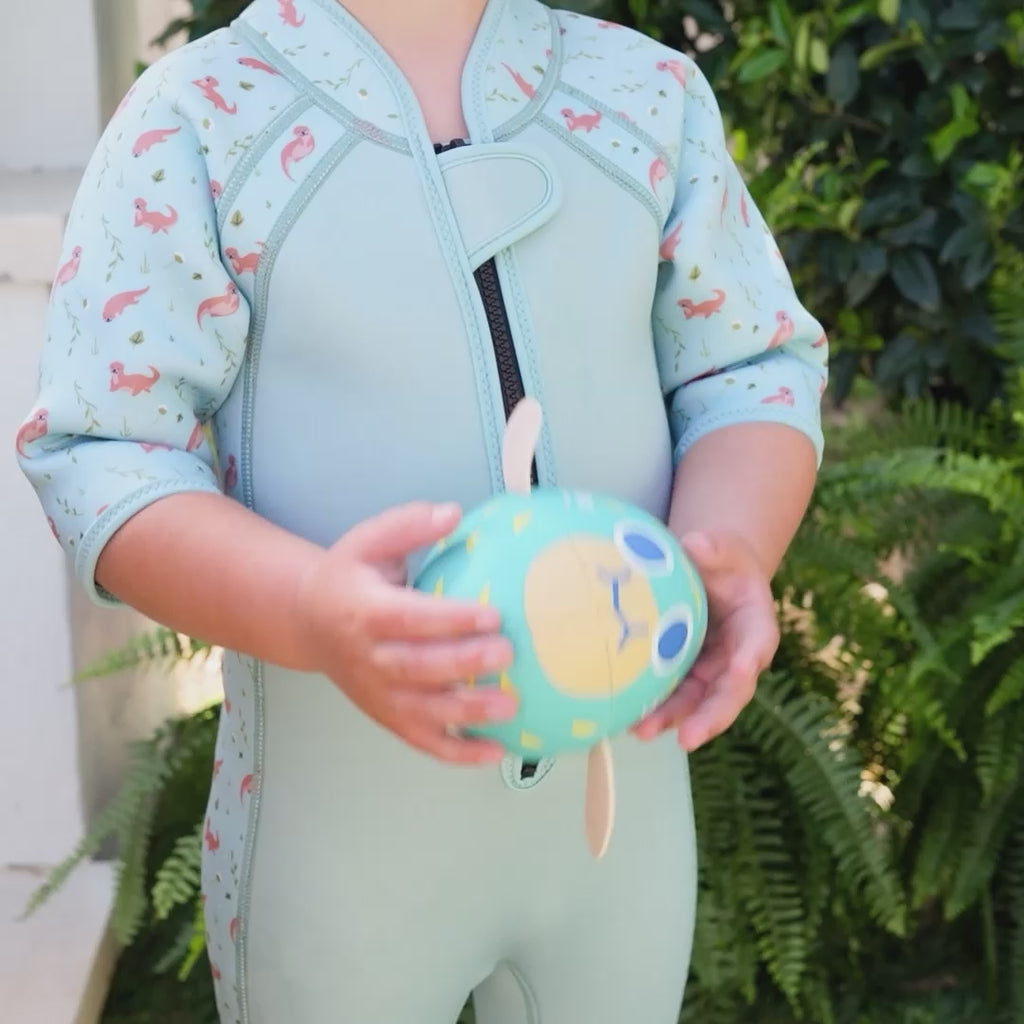little boy playing with a blue pufferfish toy wearing a shorty wetsuit playful otters video