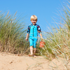 little boy on the beach stood in the reeds wearing the under the sea shorty wetsuit 
